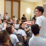 Young man speaking to a diverse group in a conference room during a workshop.
