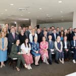 Group of diverse professionals and children at a conference or event in a modern indoor space.