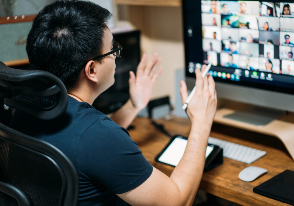 Person sitting at a desk, holding a video meeting with colleagues.